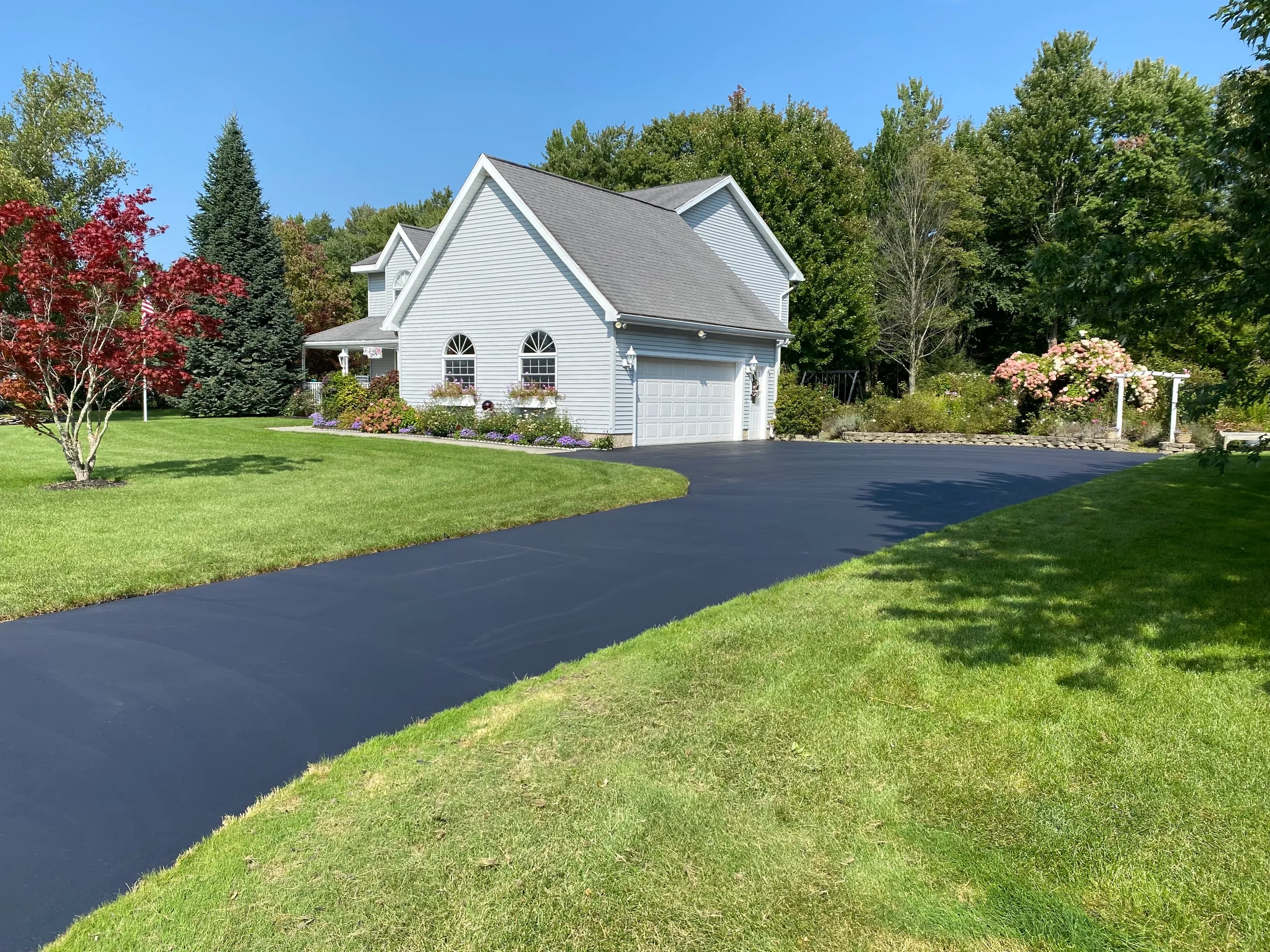 Curved residential driveway freshly sealed leading to suburban home