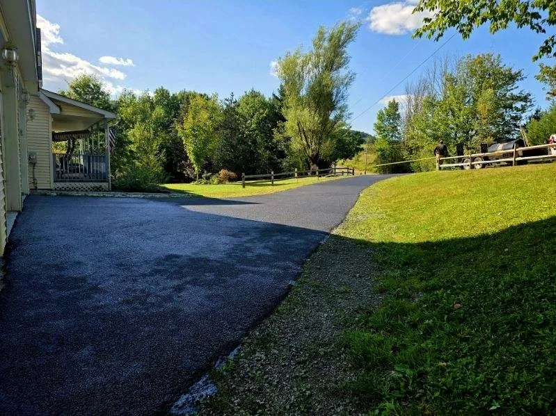 Country lane driveway freshly sealed next to farmhouse